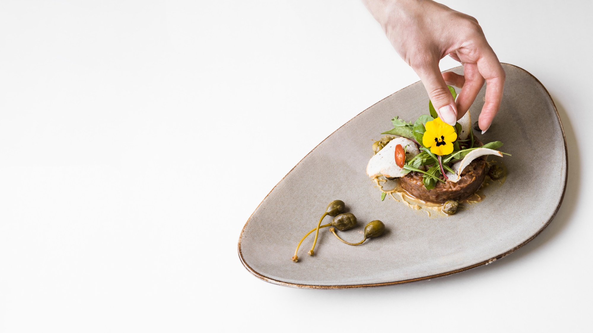 Hands plating a dish in a workshop